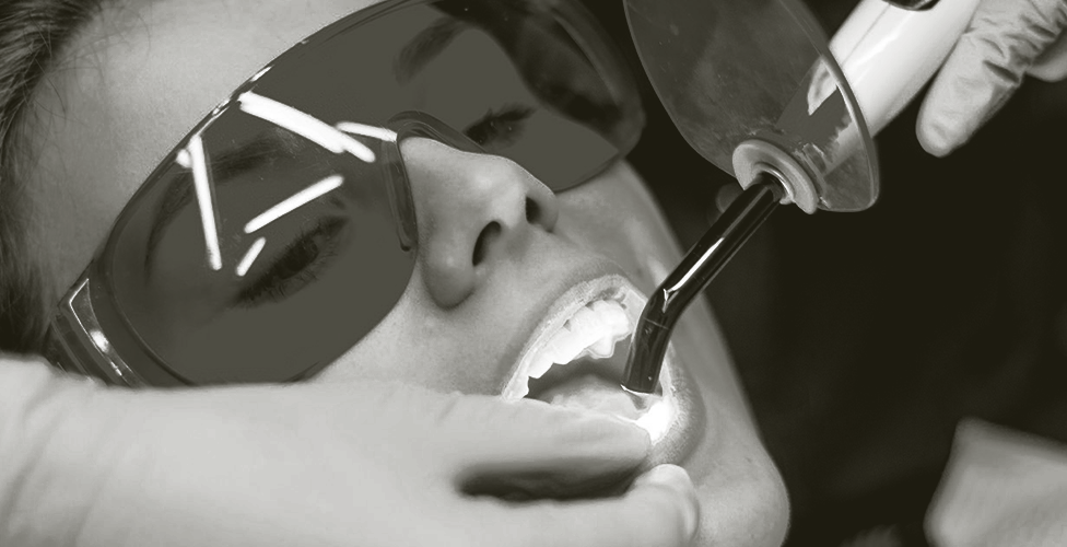 image of a person wearing safety goggles with a dental tool being used on their teeth