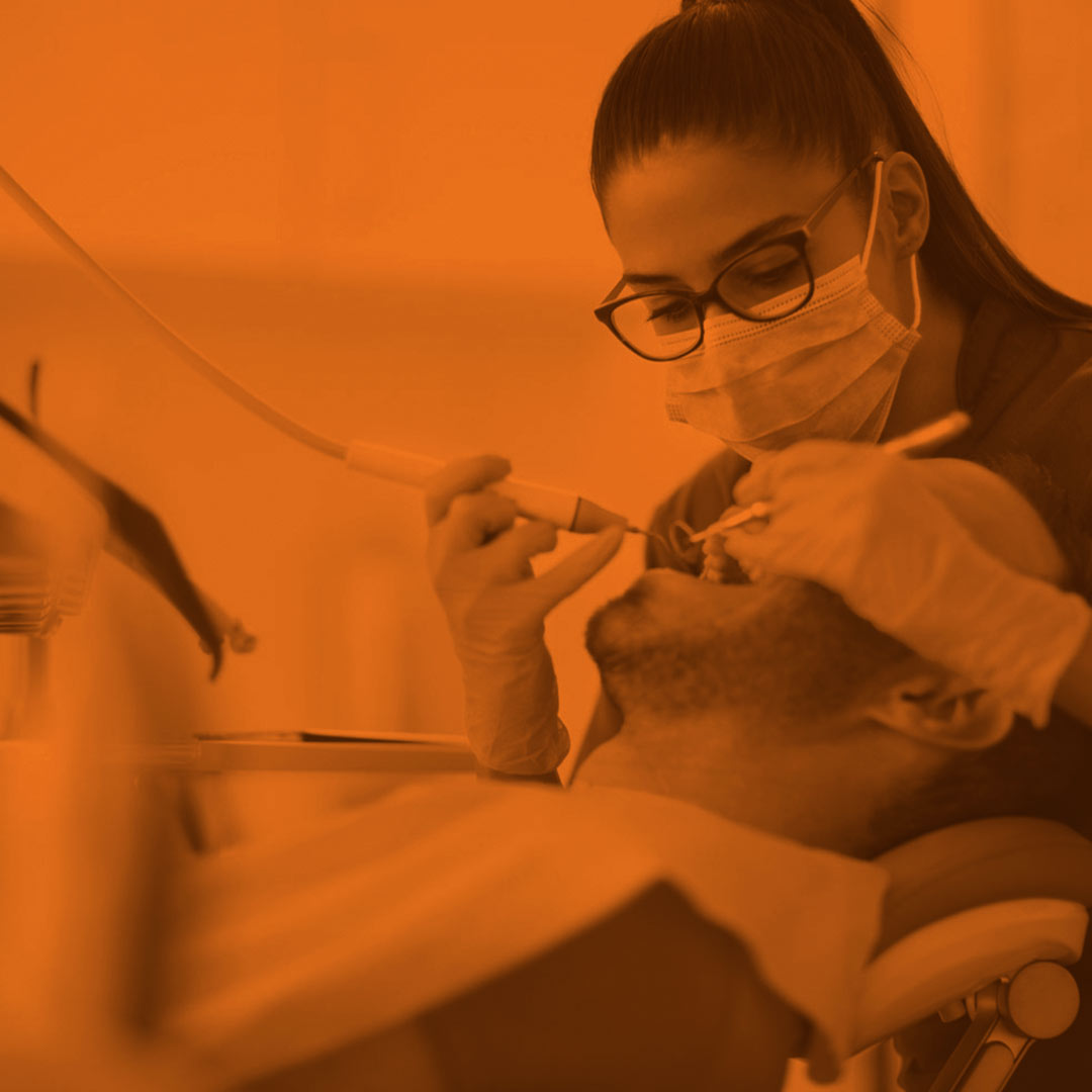 orange-scale image of a dentist working on a patient