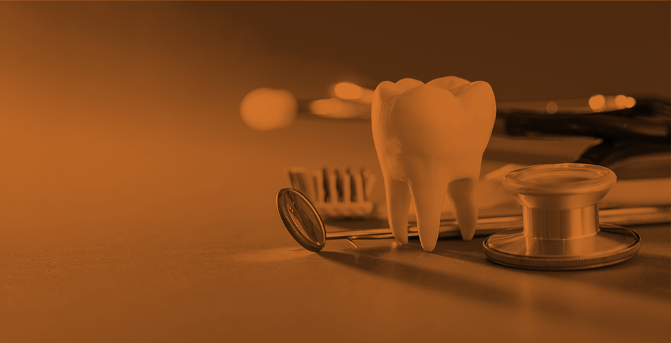 orange-scale image of a large fake tooth and various dental tools